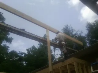 Carpenter setting a ridge beam over a new addition frame — Ice Dam Removal by Roofing Brothers in Banco