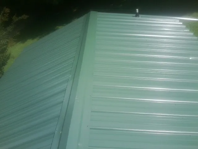 New green metal panels meeting at the ridge of a roof — Flat Roof Repair work by our crew in Banco