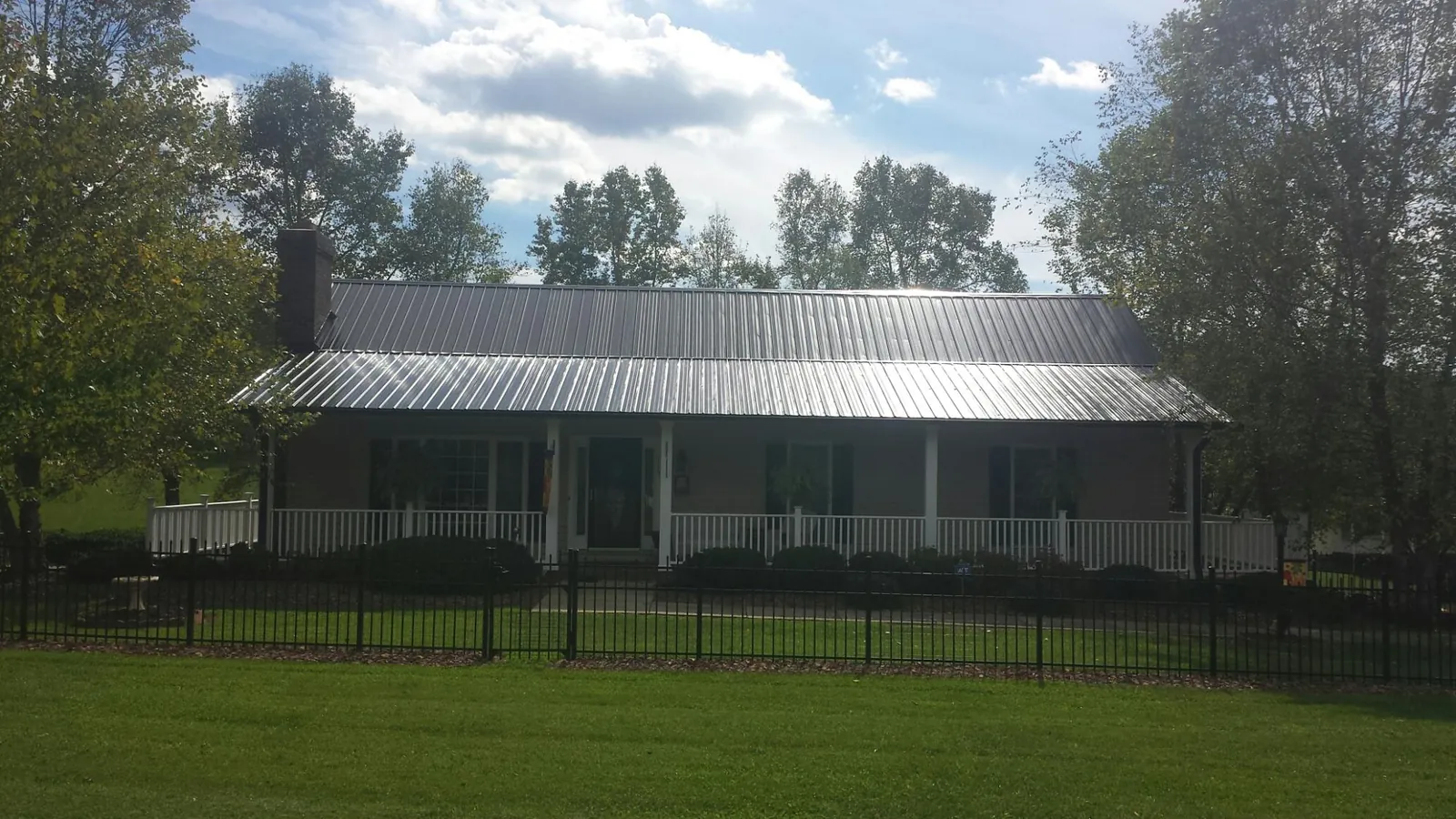 Gray metal roof on a brick ranch with a full width front porch — Gutter Guard Installation work by our crew in Banco