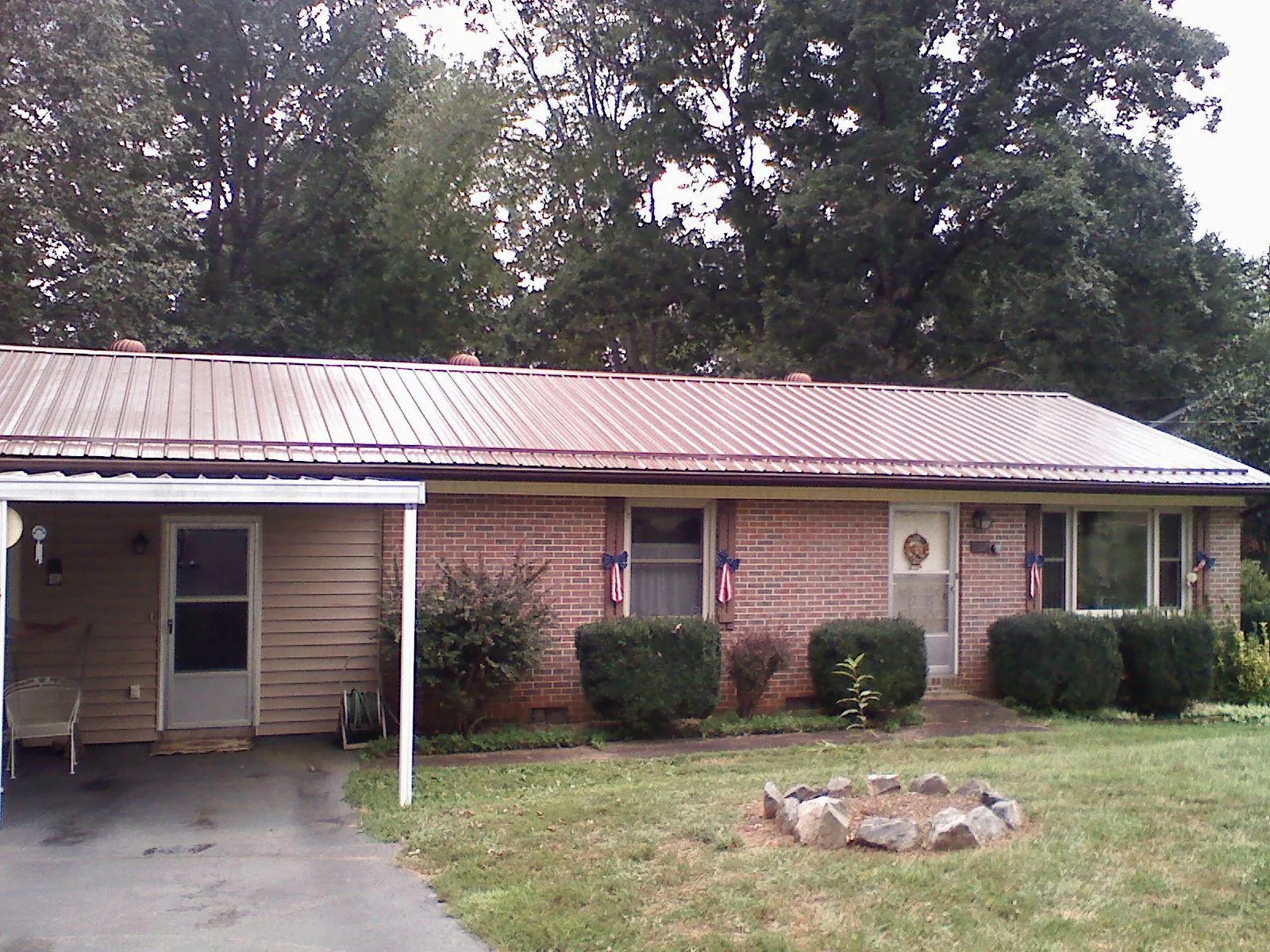Bronze metal roof and carport on a brick ranch home — Roof Repair work by our crew in Banco